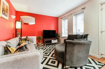 a living room with red walls and two chairs and a tv at Spacious 2-Bedroom Main Door Apartment With Private Parking in Glasgow