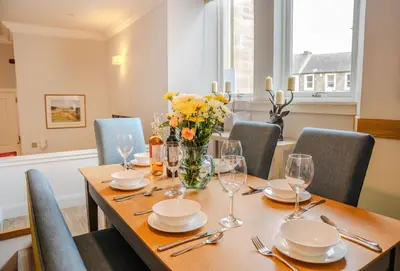 a dining room table with glasses and flowers on it at The Kinross Residence in Kinross