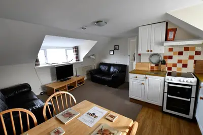 a small living room with a table and a kitchen at Argyll House Ben More in Salen