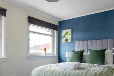 a bedroom with blue walls and a bed with green pillows at Winton House in Glasgow