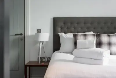 a bedroom with a bed with white pillows and a lamp at Cool urban apartment with stunning Castle views in Edinburgh