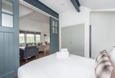 a bedroom with a white bed and a living room at Cool urban apartment with stunning Castle views in Edinburgh
