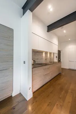 an empty kitchen with white walls and wooden floors at Cool urban apartment with stunning Castle views in Edinburgh