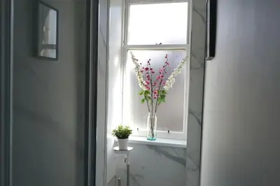 a vase of flowers sitting in a window at Falkirk City Centre Stylish Two-Bedrooms Apartment in Falkirk