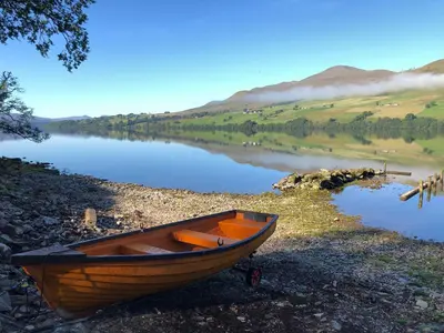 a wooden boat sitting on the shore of a lake at Bracken Lodges, Loch Tay, Linnie Lodge in Aberfeldy