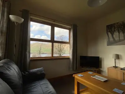 a living room with a couch and a table and a window at Bracken Lodges, Loch Tay, Linnie Lodge in Aberfeldy