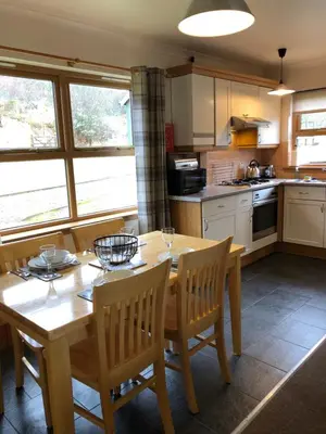 a kitchen with a wooden table and chairs in a kitchen at Bracken Lodges, Loch Tay, Linnie Lodge in Aberfeldy