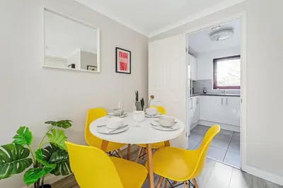 a dining room with a white table and yellow chairs at The Merchants Gem - 2Bed & Free Parking in Glasgow