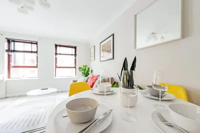 a white dining room with a white table and yellow chairs at The Merchants Gem - 2Bed & Free Parking in Glasgow