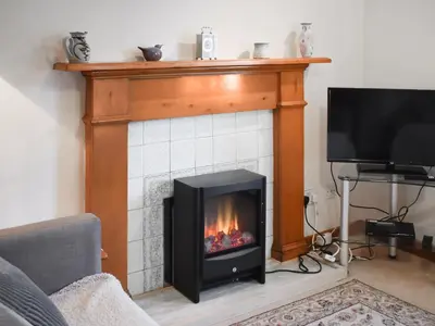 a living room with a fireplace and a tv at Bayview in Kentallen