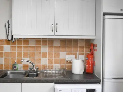a kitchen counter with a sink and white cabinets at Bayview in Kentallen