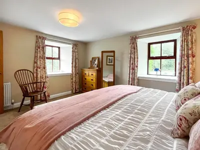 a bedroom with a large bed and two windows at The Clachan Bothy in Drumpark