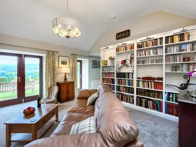 a living room with a couch and book shelves at The Clachan Bothy in Drumpark