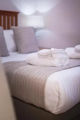 a bed with white sheets and towels on it at The Knight Residence by Mansley in Edinburgh