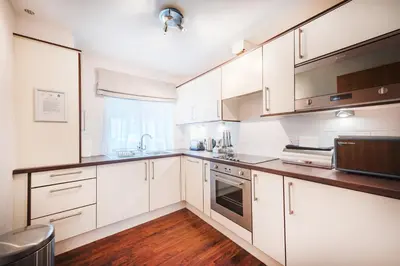 a white kitchen with wooden floors and white cabinets at The Knight Residence by Mansley in Edinburgh