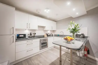 a kitchen with white cabinets and a table with a bowl of fruit at The Knight Residence by Mansley in Edinburgh