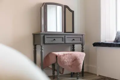a dressing table with a mirror and a pink stool at Cuthbert House in Prestwick