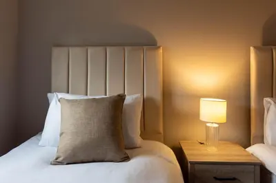 a bedroom with a bed and a lamp on a night stand at Grove House in Queensferry
