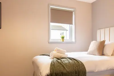 a bedroom with two beds and a window at Grove House in Queensferry