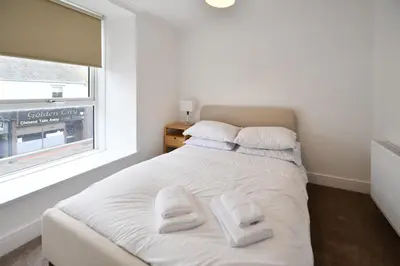 a bedroom with a white bed with two towels on it at Troon Portland Apt B in Troon