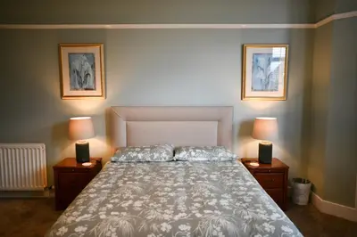 a bedroom with a large bed with two night stands at Dunvegan Apartment Troon in Troon