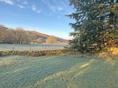 a field with a tree and a fence at Bridge Park in Killin