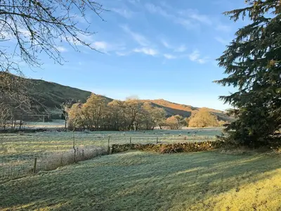 a field of grass with trees and a fence at Bridge Park in Killin