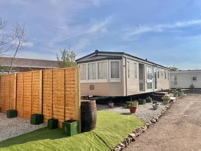 a tiny house in a yard next to a fence at Atlas 2 Bedroom Caravan - Located in Uddingston, Glasgow at Maryville Caravan Site in Uddingston