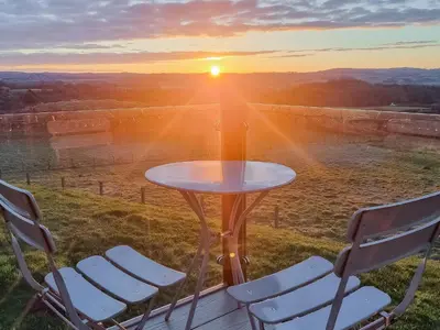 a table and chairs with the sunset in the background at Oakwood Lodge in Lochwinnoch