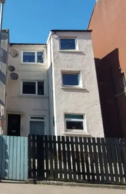 a building with a fence in front of it at The Relish - ground floor flat in Largs in Largs