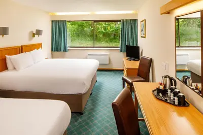 a hotel room with two beds and a desk at Mercure Livingston Hotel in Livingston