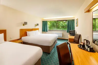 a hotel room with two beds and a desk at Mercure Livingston Hotel in Livingston