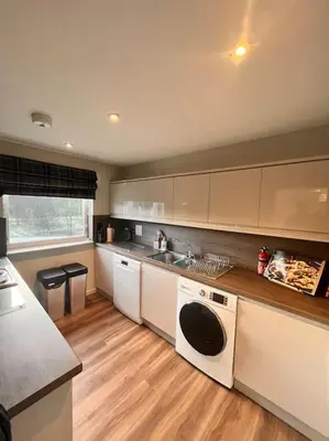a kitchen with white appliances and a wooden floor at Gleneagles Apartment in Auchterarder