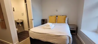 a small bedroom with a bed with yellow pillows at Hamish Apartment in Stirling