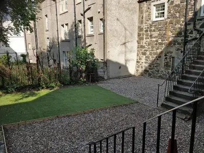 a small grass yard in front of a building at Hamish Apartment in Stirling