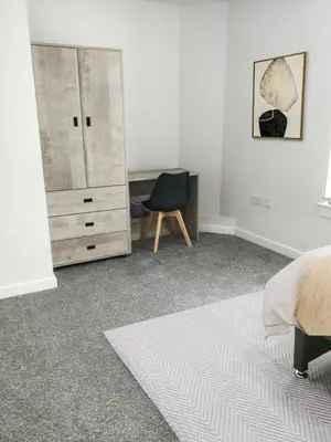 a bedroom with a bed and a chair and a dresser at Hamish Apartment in Stirling