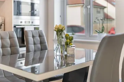 a glass vase with flowers on a table with chairs at Scenic getaway, open plan home! 2bed park for free in Eaglesham
