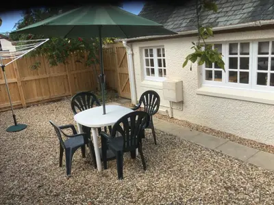 a table and chairs with an umbrella in a backyard at Cottage in Ayr