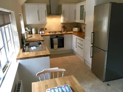 a kitchen with white cabinets and a sink and a refrigerator at Cottage in Ayr