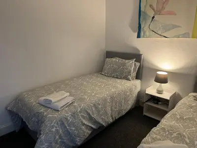 a bedroom with two beds and a lamp on a table at 140 MAIN ST GROUND LEFT in Largs