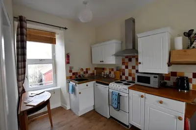 a small kitchen with white appliances and a window at Argyll House Pennyghael in Salen