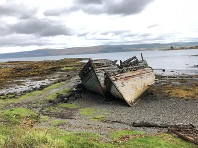 two old boats sitting on a beach near the water at Argyll House Pennyghael in Salen