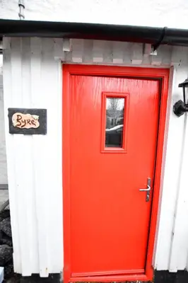 a red door on a building with a window at Argyll House The Byre in Salen