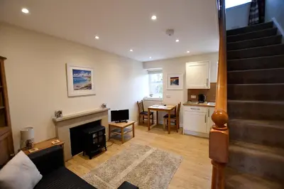 a living room with a staircase and a kitchen at Argyll House The Byre in Salen