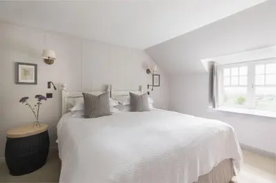 a white bedroom with a white bed and a window at Shepherds Cottage, Pentland Hills in Nine Mile Burn