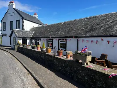 a white building with potted plants on a wall at Kingarth Hotel in Kilchattan