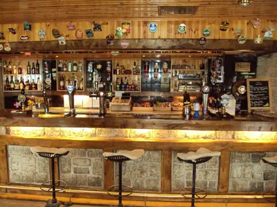 a bar with a wooden counter top with bar stools at Kingarth Hotel in Kilchattan