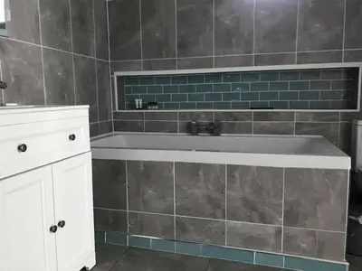 a bathroom with a tub and a tile wall at Kingarth Hotel in Kilchattan
