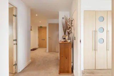 a hallway with a room with white walls and a table at Calming Sea View City Apartment in Edinburgh