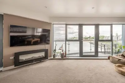 a living room with a fireplace and a large window at Calming Sea View City Apartment in Edinburgh